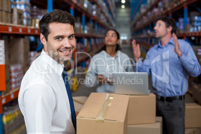 Focus of manager holding cardboard box and smiling in front of w