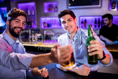 Portrait of men showing glass of beer and beer bottle