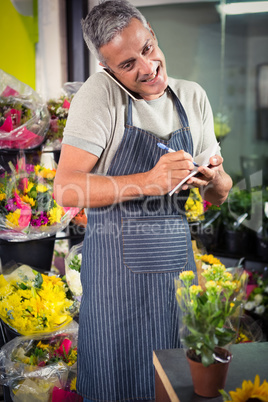 Male florist taking order on mobile phone