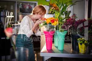 Portrait of female florist smelling rose flowers