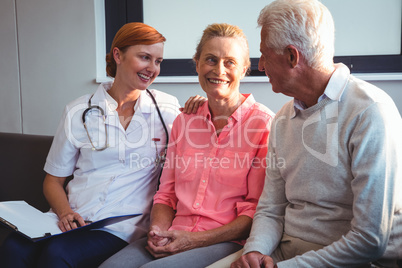 Nurse and senior couple sitting on a couch