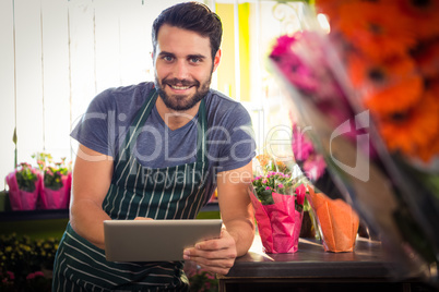 Male florist holding digital tablet at his flower shop