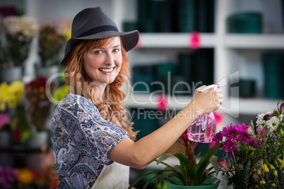 Smiling florist spraying water on flowers in flower shop