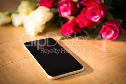 Yellow and red roses with smartphone on the wooden table