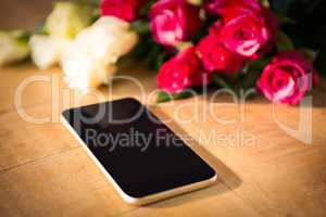Yellow and red roses with smartphone on the wooden table