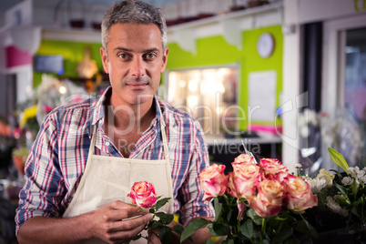 Male florist holding rose at flower shop