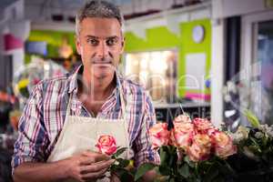 Male florist holding rose at flower shop
