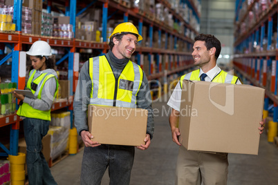 Workers holding box looking each other