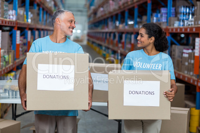 Happy volunteers are holding donations boxes and looking each ot