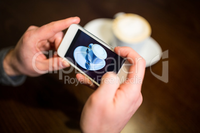Man taking photo of coffee cup