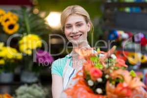 Female florist holding flower bouquet in flower shop