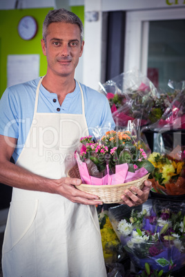Male florist carrying plant pot in wicker basket
