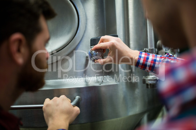 Maintenance workers examining brewery machine