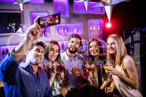 Group of friends taking selfie while having glasses of cocktail