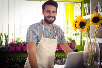 Male florist with laptop at his flower shop