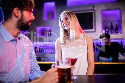 Friends having glass of beer and red martini at bar counter