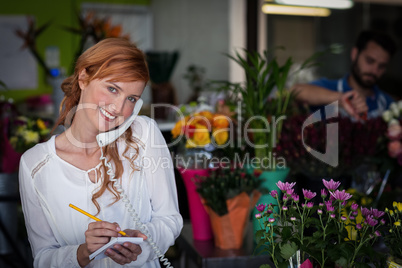 Female florist taking an order on telephone
