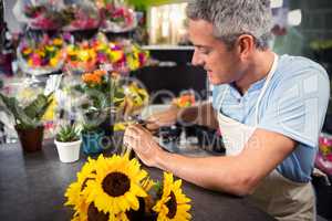 Male florist trimming stems of flowers at flower shop