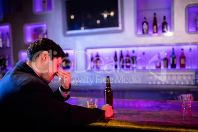 Depressed man having beer at bar counter