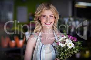 Happy female florist holding bunch of flowers in flower shop