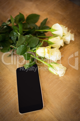 Yellow roses and smartphone on the wooden table