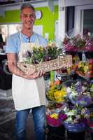 Male florist carrying plant pot in wicker basket