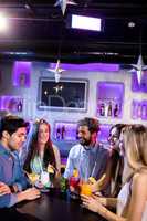 Group of friends interacting with each other at bar counter whil