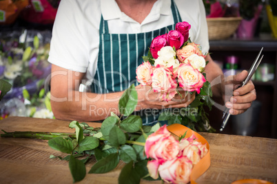 Male florist holding bunch of roses and shears