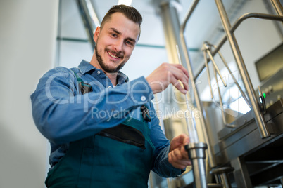Brewer checking beer with hydrometer