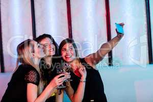 Smiling friends taking a selfie from mobile phone while having w