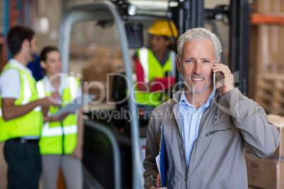 Portrait of manager is talking on the phone and holding a clipbo