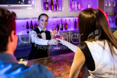 Barmaid serving drink to woman