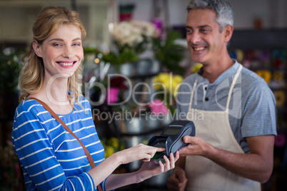 Smiling woman making payment with her credit card to florist