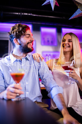 Friends interacting with each other at bar counter while having