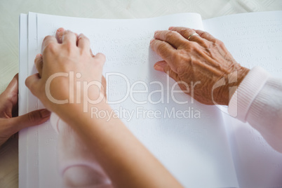 Nurse helping senior woman with braille