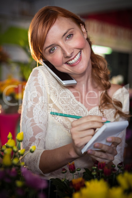 Female florist taking order on mobile phone