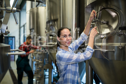 Female maintenance worker examining brewery machine