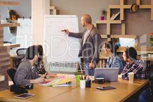 Male graphic designer discussing chart on white board with cowor