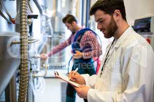 Maintenance workers examining brewery machine