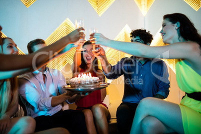 Group of smiling friends toasting a glass of champagne while cel