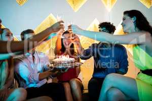 Group of smiling friends toasting a glass of champagne while cel