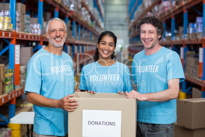 Happy volunteers are smiling and posing with a donations box