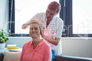 Nurse giving head massage to senior woman