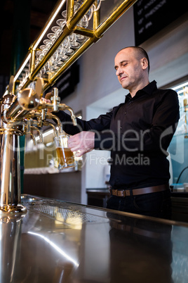 Brewer filling beer in beer glass from beer pump