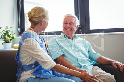 Nurse and senior man sitting on sofa