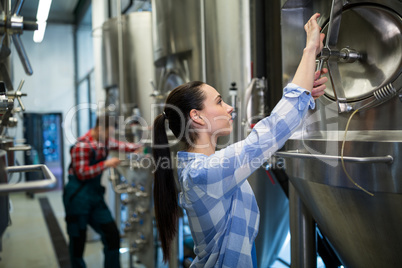 Female maintenance worker examining brewery machine