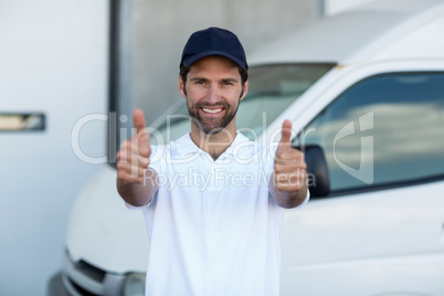 Portrait of delivery man is posing and smiling with thumbs up