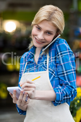 Female florist taking order on mobile phone in flower shop