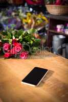 Bunch of red roses and smartphone on the wooden table