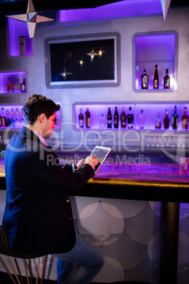 Man using digital tablet at bar counter